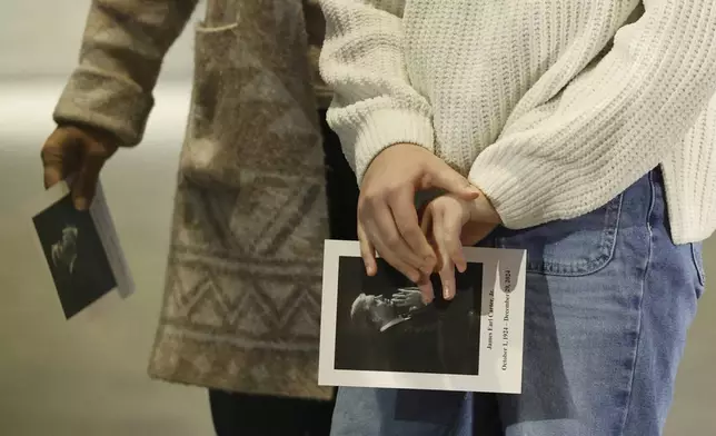 Mourners hold remembrance cards as they view the casket of former President Jimmy Carter as he lies in repose at the Jimmy Carter Presidential Library and Museum in Atlanta, Monday, Jan. 6, 2025. Carter died Dec. 29 at the age of 100. (Erik S. Lesser/Pool via AP)