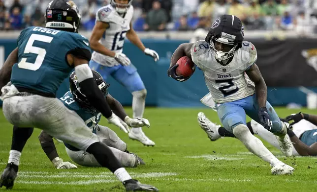 Tennessee Titans running back Tyjae Spears (2) runs the ball against the Jacksonville Jaguars safety Andre Cisco (5) and linebacker Devin Lloyd (33) during the second half of an NFL football game, Sunday, Dec. 29, 2024, in Jacksonville, Fla. (AP Photo/Phelan M. Ebenhack)