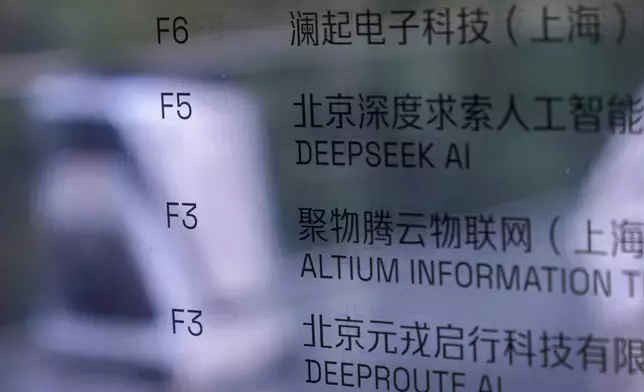An AI robot moves past an office information board showing the DeepSeek smartphone apps company in Beijing, Tuesday, Jan. 28, 2025. (AP Photo/Andy Wong)