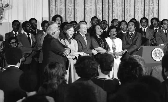 FILE - Dr. Martin Luther King Sr., Rosalynn Carter, President Jimmy Carter, Coretta Scott King, Christine Parris King, sister of the late Dr. King, and U.N. Ambassador Andrew Young sing during a reception honoring friends of the Martin Luther King Jr. Center for Social Change in Washington on Oct. 3, 1978. (AP Photo/Barry Thumma, File)