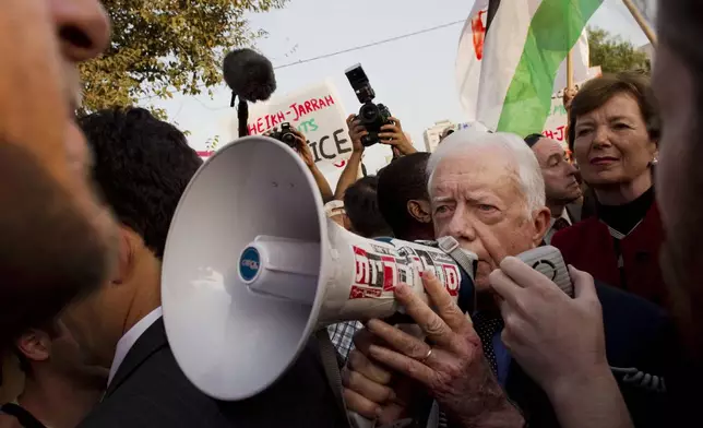 FILE - Former president of Ireland Mary Robinson, background right, looks at former U.S. President Jimmy Carter, center, while visiting a weekly protest in the east Jerusalem neighborhood of Sheikh Jarrah, on Oct. 22, 2010. The protest was organized by groups supporting Palestinians evicted from their homes in east Jerusalem by Israeli authorities. (AP Photo/Bernat Armangue, File)