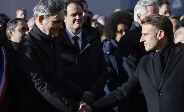 French President Emmanuel Macron, right, shakes hands with Laurent Sourisseau, known as "Riss", publishing director of French satirical magazine "Charlie Hebdo" during commemorations marking 10 years since an Islamist attack on the Charlie Hebdo satirical newspaper and the Hypercacher jewish supermarket, outside the weekly's former offices in Paris Tuesday Jan. 7, 2025. (Ludovic Marin, Pool via AP)