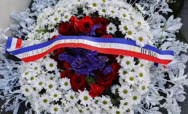 A wreath of flowers from Charlie Hebdo magazine is seen during a commemoration marking 10 years since an Islamist attack on the Charlie Hebdo satirical newspaper and the Hypercacher jewish supermarket, outside the weekly's former offices in Paris Tuesday Jan. 7, 2025. A decade after gunmen stormed the offices of satirical newspaper Charlie Hebdo in a deadly assault that shook France to its core, the nation is pausing to honor the victims and grapple with the evolving challenges of free expression and terrorism. (Ludovic Marin, Pool via AP)