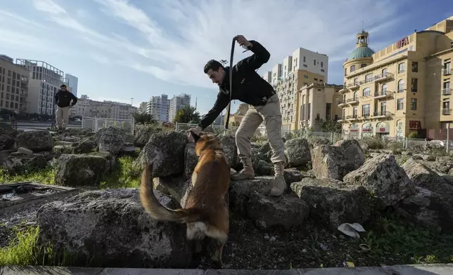 A Lebanese army soldier with a sniffer dog checks a road that leads to the parliament building while lawmakers gather to elect a president in Beirut, Lebanon, Thursday, Jan. 9, 2025. (AP Photo/Bilal Hussein)