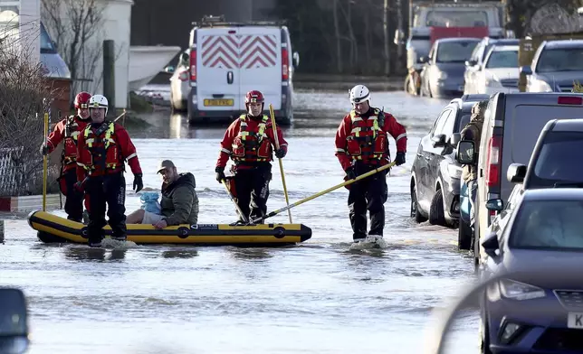 Firemen help residents in the flooded area of Barrow Upon Soar, England, Tuesday, Jan. 7, 2025.(AP Photo/Darren Staples)