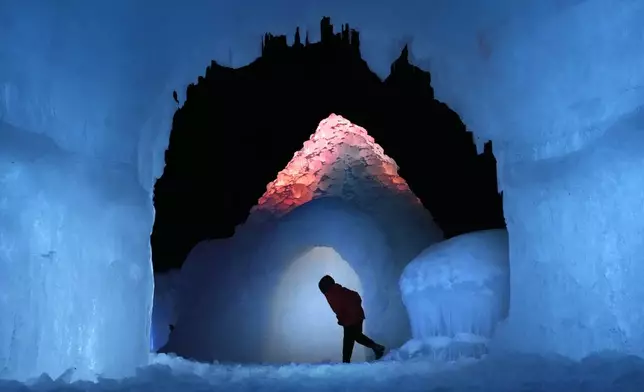 A boy peaks into an igloo at the Ice Castles, Friday, Jan. 10, 2025, in North Woodstock, N.H. (AP Photo/Robert F. Bukaty)