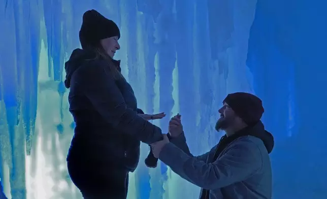Jessica Sullivan holds out her ring finger after accepting a surprise marriage proposal from longtime boyfriend Brian Jacques, of Fairhaven, Mass., at Ice Castles, Friday, Jan. 10, 2025, in North Woodstock, N.H. (AP Photo/Robert F. Bukaty)