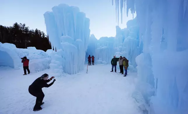 Visitors pose for a photo on opening day at the Ice Castles, Friday, Jan. 10, 2025, in North Woodstock, N.H. (AP Photo/Robert F. Bukaty)