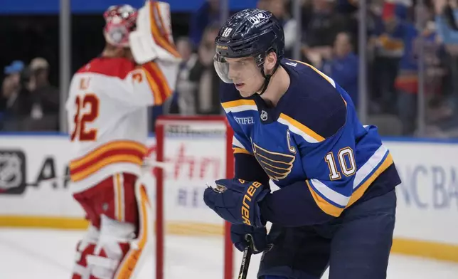 St. Louis Blues' Brayden Schenn (10) skates after scoring past Calgary Flames goaltender Dustin Wolf, left, during the second period of an NHL hockey game Thursday, Jan. 16, 2025, in St. Louis. (AP Photo/Jeff Roberson)