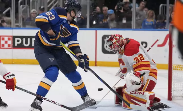 St. Louis Blues' Jake Neighbours (63) is unable to score past Calgary Flames goaltender Dustin Wolf (32) during the second period of an NHL hockey game Thursday, Jan. 16, 2025, in St. Louis. (AP Photo/Jeff Roberson)