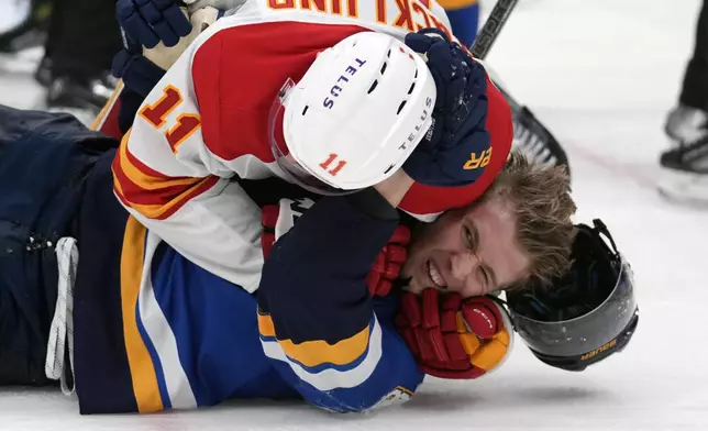 St. Louis Blues' Dylan Holloway and Calgary Flames' Mikael Backlund (11) fight during the second period of an NHL hockey game Thursday, Jan. 16, 2025, in St. Louis. (AP Photo/Jeff Roberson)