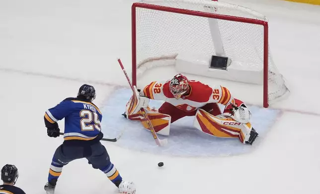 Calgary Flames goaltender Dustin Wolf (32) stops a shot by St. Louis Blues' Jordan Kyrou (25) during the third period of an NHL hockey game Thursday, Jan. 16, 2025, in St. Louis. (AP Photo/Jeff Roberson)