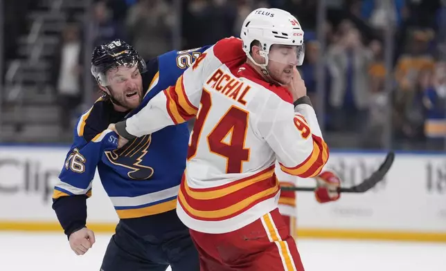 St. Louis Blues' Nathan Walker, left, and Calgary Flames' Brayden Pachal (94) fight during the third period of an NHL hockey game Thursday, Jan. 16, 2025, in St. Louis. (AP Photo/Jeff Roberson)