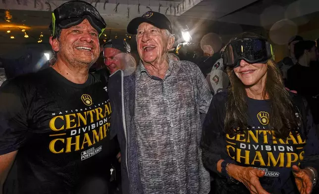 FILE - Milwaukee Brewers' owner Mark Attanasio and wife Debbie celebrate with broadcaster Bob Uecker after clinching the National League Central Division after a baseball game against the St. Louis Cardinals, Sept. 26, 2023, in Milwaukee. (AP Photo/Morry Gash)