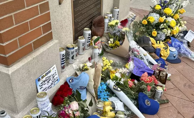Items are left at the base of a statue of Bob Uecker outside American Family Field in Milwaukee, Thursday, Jan. 16, 2025. (AP Photo/Steve Megargee)
