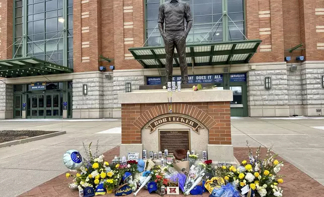 Items are left at the base of a statue of Bob Uecker outside American Family Field in Milwaukee, Thursday, Jan. 16, 2025. (AP Photo/Steve Megargee)