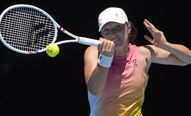 Iga Swiatek of Poland plays a forehand return to Emma Raducanu of Britain during their third round match at the Australian Open tennis championship in Melbourne, Australia, Saturday, Jan. 18, 2025. (AP Photo/Asanka Brendon Ratnayake)