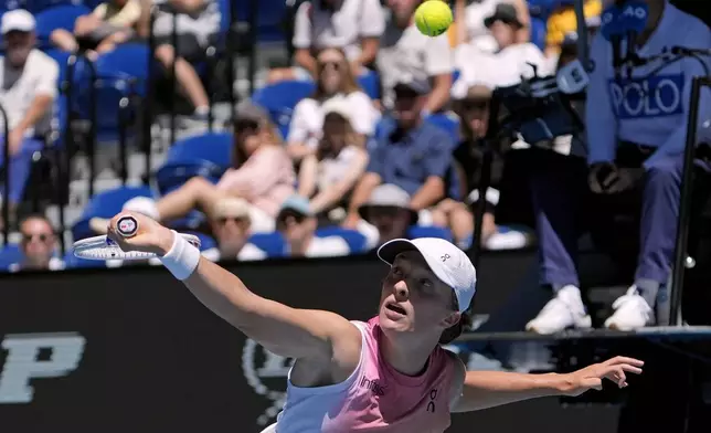 Iga Swiatek of Poland plays a backhand return to Emma Raducanu of Britain during their third round match at the Australian Open tennis championship in Melbourne, Australia, Saturday, Jan. 18, 2025. (AP Photo/Asanka Brendon Ratnayake)
