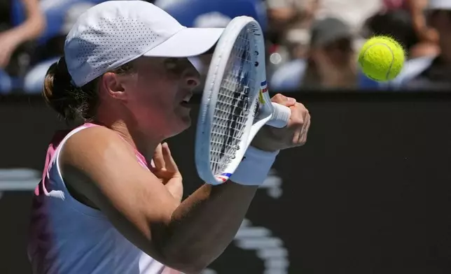 Iga Swiatek of Poland plays a forehand return to Emma Raducanu of Britain during their third round match at the Australian Open tennis championship in Melbourne, Australia, Saturday, Jan. 18, 2025. (AP Photo/Asanka Brendon Ratnayake)