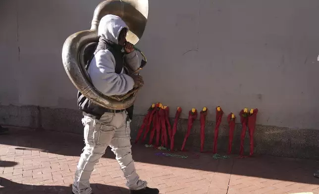 Tyrone Johnson walks past a flower memorial on Canal and Bourbon Street, Thursday, Jan. 2, 2025 in New Orleans. (AP Photo/George Walker IV)