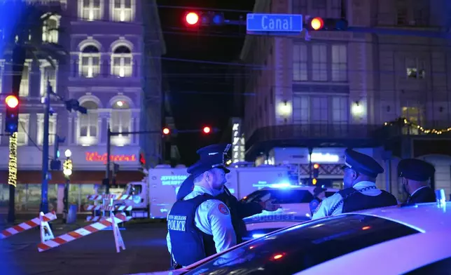 Police officers stand near the scene where a vehicle drove into a crowd on New Orleans' Canal and Bourbon streets, Wednesday, Jan. 1, 2025. (AP Photo/George Walker IV)