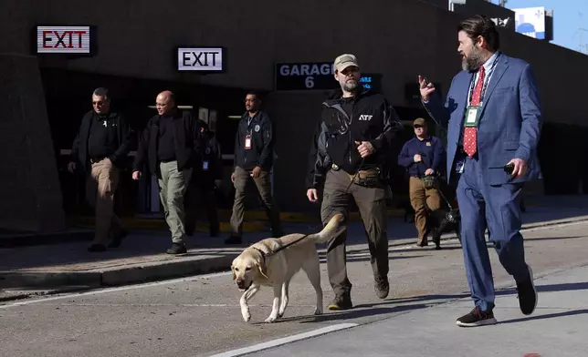 Security with bomb sniffing dogs patrol the area around the Superdome ahead of the Sugar Bowl NCAA College Football Playoff game, Thursday, Jan. 2, 2025, in New Orleans. (AP Photo/Butch Dill)