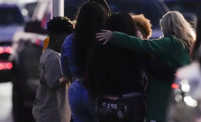 Neighbors embrace as they stand outside the police lines surrounding a location in Houston, Texas, Wednesday, Jan. 1, 2025, where police personnel investigate the place suspected to be associated with an attacker in a deadly rampage in New Orleans. (Brett Coomer/Houston Chronicle via AP)