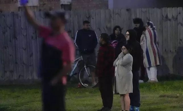 Neighbors stand and watch outside the police lines surrounding a location in Houston, Texas, Wednesday, Jan. 1, 2025, where police personnel investigate the place suspected to be associated with an attacker in a deadly rampage in New Orleans. (Brett Coomer/Houston Chronicle via AP)