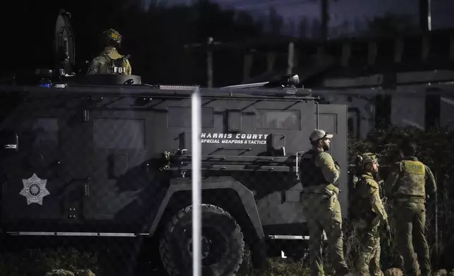 Law enforcement officers stand behind a SWAT vehicle near a location in Houston, Texas, Wednesday, Jan. 1, 2025, where police personnel investigate the place suspected to be associated with an attacker in a deadly rampage in New Orleans. (Brett Coomer/Houston Chronicle via AP)