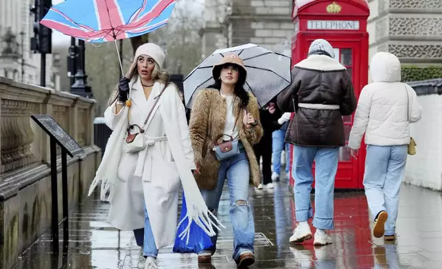 A woman has her umbrella upturned by the wind whilst walking near Parliament Square, London, Sunday Jan. 5, 2025. (Jonathan Brady/PA via AP)