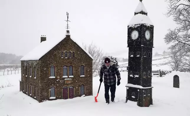 Lowson Robinson is pictured in the heavy snow with his scaled miniature famous landmarks which are located in his garden in Nenthead, England, as the severe weather continues across England, Sunday, Jan. 5, 2025. (AP Photo/Scott Heppell)