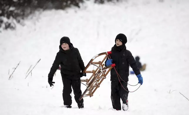 Boys are seen with a sledge on a hill with Durham Cathedral which is surrounded by heavy snow in Durham, North East England, as the severe weather continues across England, Sunday, Jan. 5, 2025. (AP Photo/Scott Heppell)