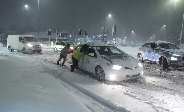 People help to push cars stuck in snow in Leeds, England, Sunday, Jan. 5, 2025. (Danny Lawson/PA via AP)