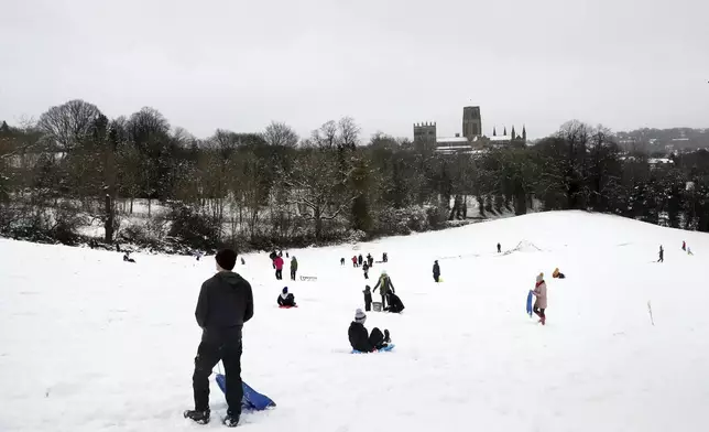 Members of the public are seen sledging on a hill with Durham Cathedral which is surrounded by heavy snow in Durham, North East England, as the severe weather continues across England, Sunday, Jan. 5, 2025. (AP Photo/Scott Heppell)