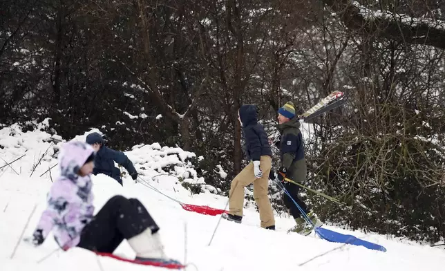 A man is seen with his son as they ski and sledge on a hill with Durham Cathedral which is surrounded by heavy snow in Durham, North East England, as the severe weather continues across England, Sunday, Jan. 5, 2025. (AP Photo/Scott Heppell)