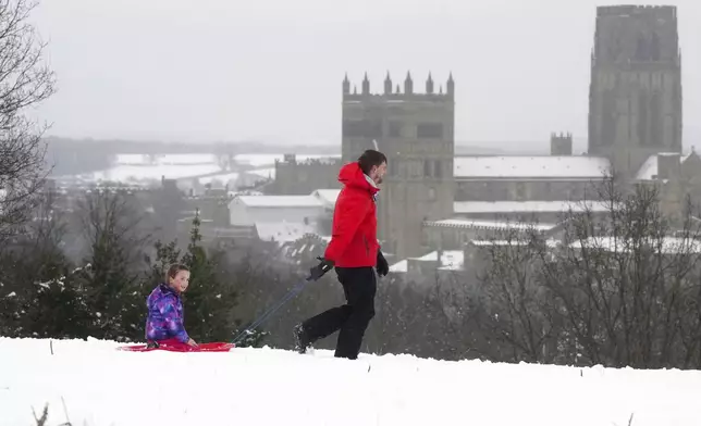 People sledging near Durham Cathedral in Durham, north England, Sunday Jan. 5, 2025, as heavy overnight snow causes disruption across the UK as the cold start to the new year continues. (Owen Humphreys/PA via AP)