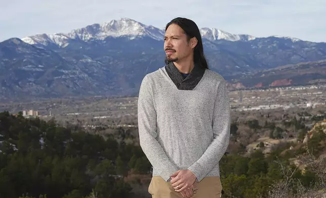 Lane Belone poses with Pikes Peak in the background on an overlook in Palmer Park, Thursday, Dec. 19, 2024, in Colorado Springs, Colo. (AP Photo/David Zalubowski)