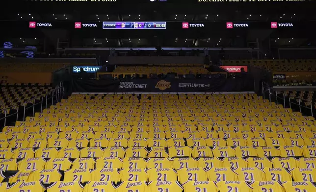 Jerseys with the number of former Los Angeles Lakers player Michel Cooper are left for fans on seats before an NBA basketball game between the Lakers and the San Antonio Spurs, Monday, Jan. 13, 2025, in Los Angeles. Cooper's No. 21 jersey will be raised into the rafters during halftime. (AP Photo/Kevork Djansezian)