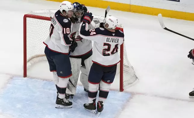 Columbus Blue Jackets goaltender Jet Greaves celebrates a 2-1 victory over the St. Louis Blues with teammates Dmitri Voronkov (10) and Mathieu Olivier (24) following an NHL hockey game Saturday, Jan. 11, 2025, in St. Louis. (AP Photo/Jeff Roberson)