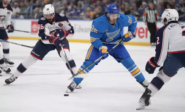 St. Louis Blues' Jordan Kyrou (25) handles the puck as Columbus Blue Jackets' Kirill Marchenko (86) and Jake Christiansen (2) defend during the second period of an NHL hockey game Saturday, Jan. 11, 2025, in St. Louis. (AP Photo/Jeff Roberson)