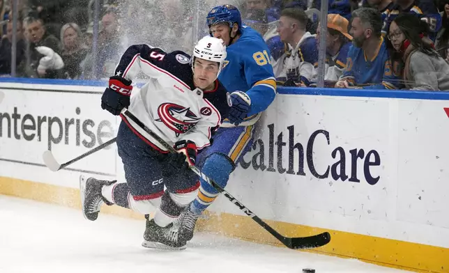Columbus Blue Jackets' Denton Mateychuk (5) looks to pass as St. Louis Blues' Dylan Holloway (81) slams into the boards during the second period of an NHL hockey game Saturday, Jan. 11, 2025, in St. Louis. (AP Photo/Jeff Roberson)