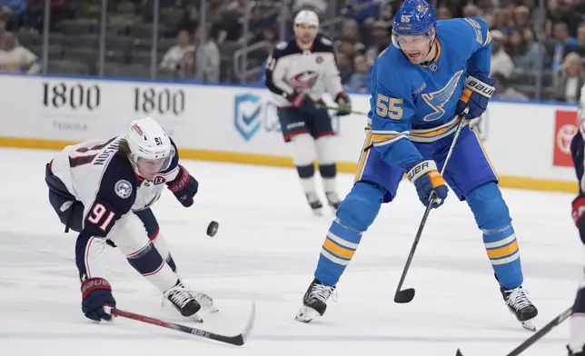 St. Louis Blues' Colton Parayko (55) and Columbus Blue Jackets' Kent Johnson (91) chase after a loose puck during the second period of an NHL hockey game Saturday, Jan. 11, 2025, in St. Louis. (AP Photo/Jeff Roberson)
