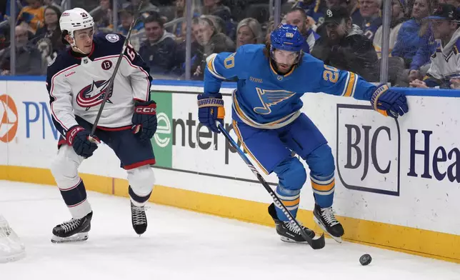 Columbus Blue Jackets' Luca Del Bel Belluz (65) and St. Louis Blues' Brandon Saad (20) chase after a loose puck during the second period of an NHL hockey game Saturday, Jan. 11, 2025, in St. Louis. (AP Photo/Jeff Roberson)