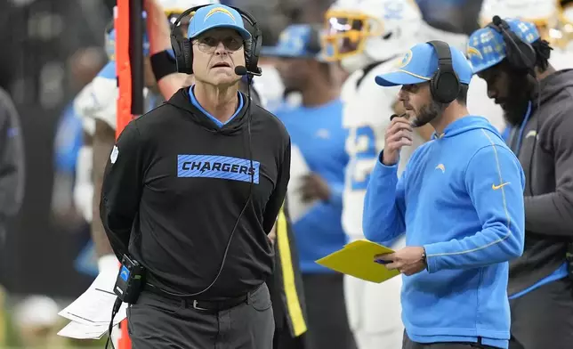 Los Angeles Chargers head coach Jim Harbaugh, left, walks on the sideline during the first half of an NFL football game against the Las Vegas Raiders in Las Vegas, Sunday, Jan. 5, 2025. (AP Photo/John Locher)