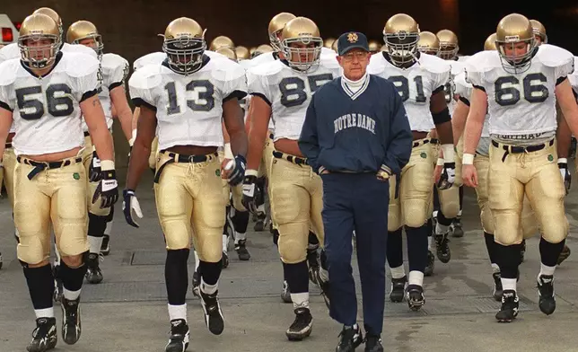 FILE - Notre Dame's head coach Lou Holtz and the Fighting Irish walk onto the field of the Los Angeles Coliseum to warm up for an NCAA college football game against Southern California Saturday, Nov. 30, 1996 in Los Angeles. (AP Photo/Kevork Djansezian, File)