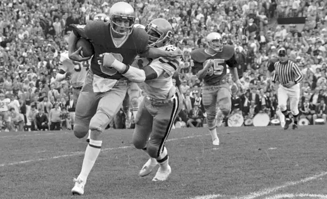 FILE - Notre Dame's Joe Montana tries to brush off Reggie Wilkes of Georgia Tech during his six-yard gain in first quarter of an NCAA college football game, Nov. 7, 1977 game at South Bend, Ind. (AP Photo/File)