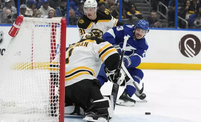 Tampa Bay Lightning center Michael Eyssimont (23) gets held by Boston Bruins defenseman Nikita Zadorov (91) as he tries to get a shot on goaltender Jeremy Swayman (1) during the second period of an NHL hockey game Thursday, Jan. 9, 2025, in Tampa, Fla. (AP Photo/Chris O'Meara)