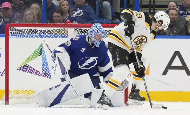 Boston Bruins center John Beecher (19) tries to control the puck in front of Tampa Bay Lightning goaltender Andrei Vasilevskiy (88) during the second period of an NHL hockey game Thursday, Jan. 9, 2025, in Tampa, Fla. (AP Photo/Chris O'Meara)