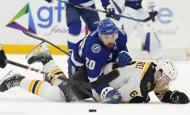 Tampa Bay Lightning left wing Nick Paul (20) knocks down Boston Bruins defenseman Mason Lohrei (6) during the second period of an NHL hockey game Thursday, Jan. 9, 2025, in Tampa, Fla. (AP Photo/Chris O'Meara)