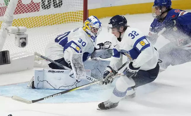 Finland goaltender Petteri Rimpinen (30) looks on as teammate Emil Hemming (32) controls the puck away from United States forward Ryan Leonard (9) during third-period IIHF World Junior Hockey Championship gold medal game action in Ottawa, Ontario, Sunday, Jan. 5, 2025. (Adrian Wyld/The Canadian Press via AP)